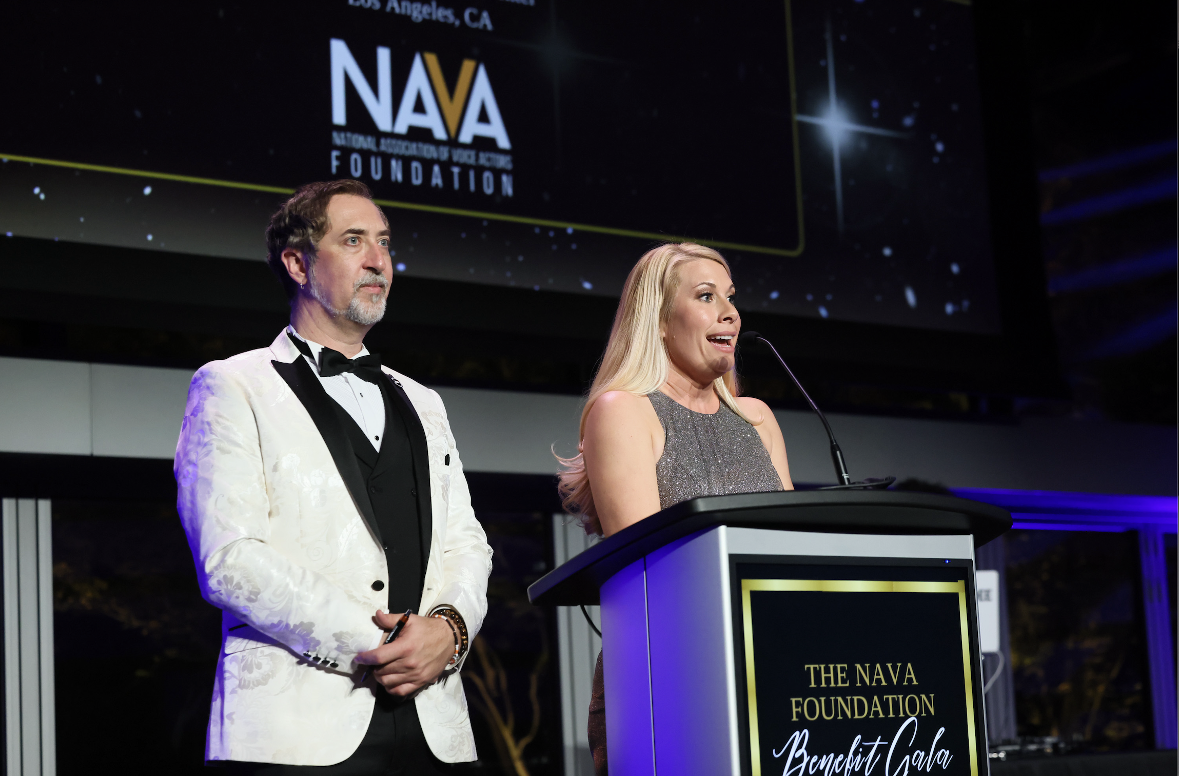 man and woman on stage speaking at a podium